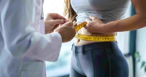 A healthcare professional measures a woman’s waist with a tape measure during a Medical Weight Loss consultation in Liberty Hill, TX.